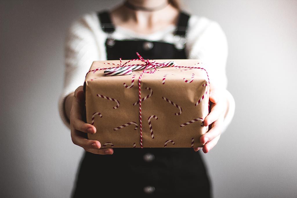 two hands holding a present wrapped in brown kraft paper