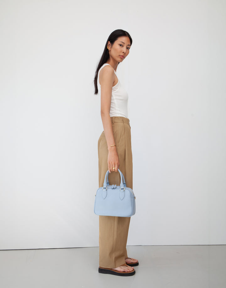 hyer goods la corsa pale blue leather bowling bag held by model's side #color_pale-blue
