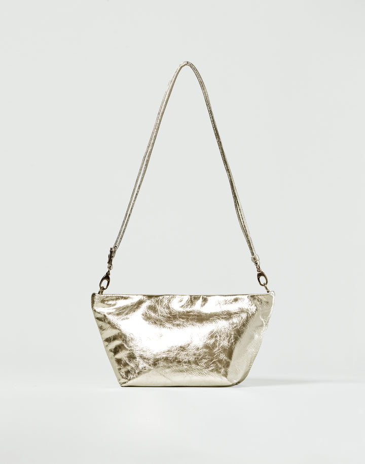 a gold leather shoulder bag with thin strap on a grey background #color_gold