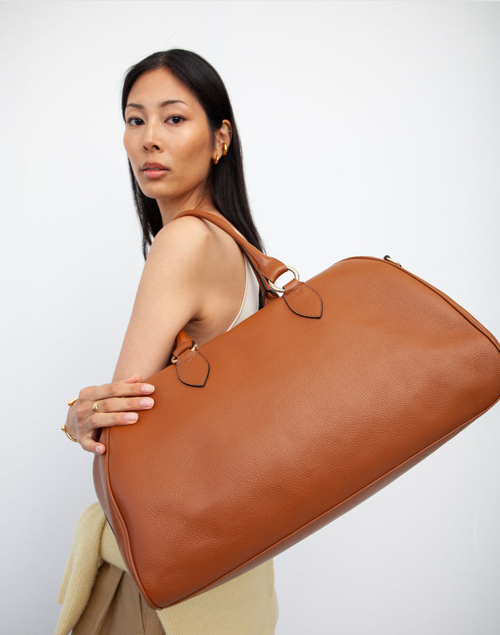 HYER GOODS tan leather la via weekender duffel bag close up on models shoulder #color_cognac