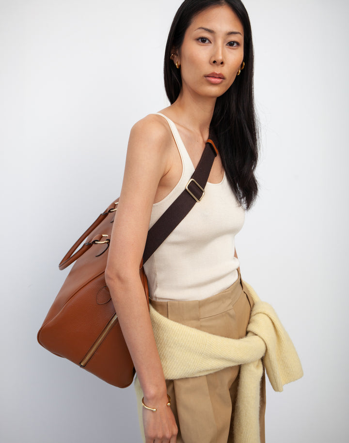 HYER GOODS tan leather la via weekender duffel bag worn as a crossbody duffel #color_cognac